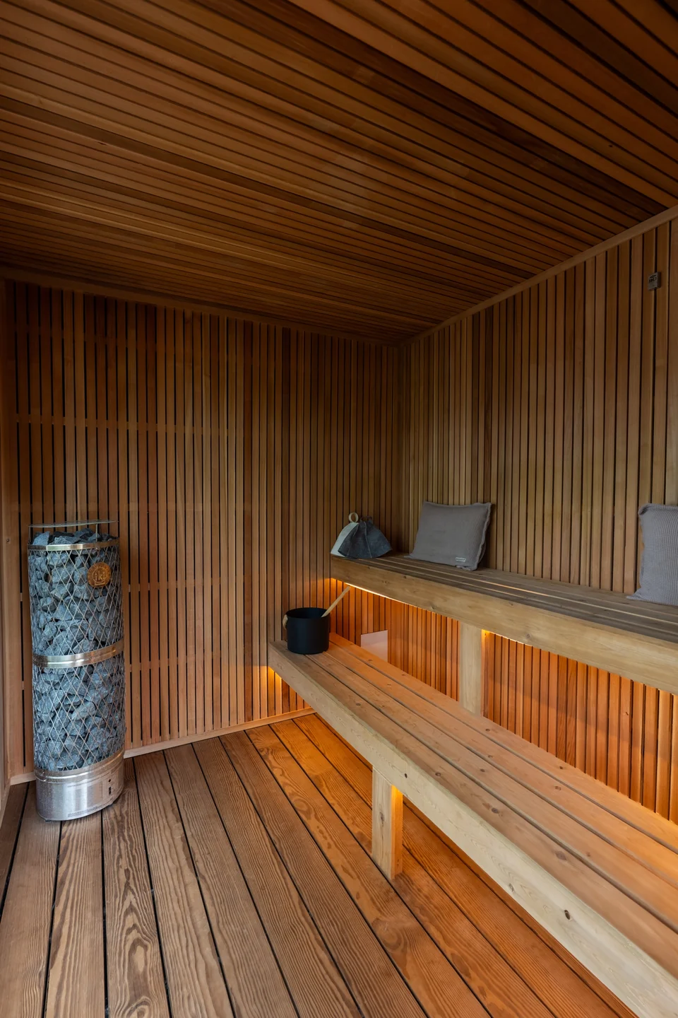 IKI stone-tower heater beside two illuminated cedar bench tiers