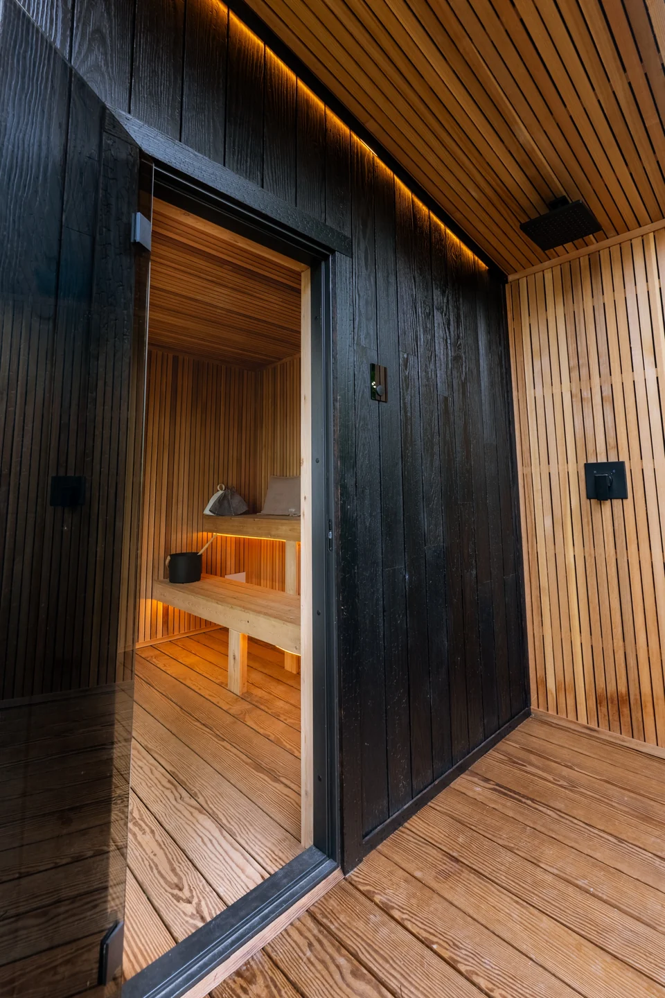 Sheltered cedar porch and glass entrance into the illuminated 212 sauna