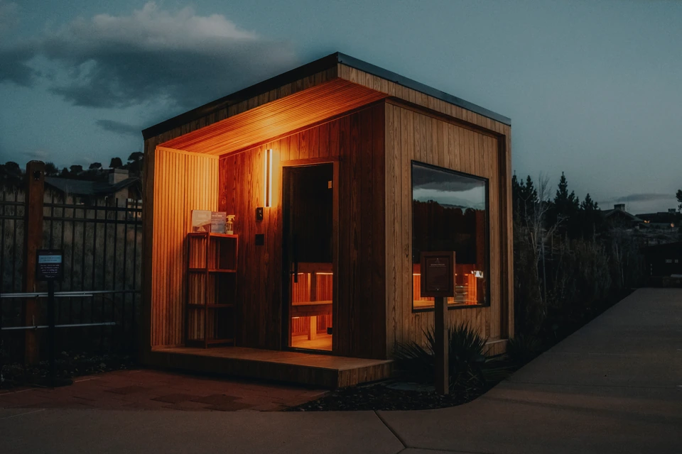 Sauna at Red Ledges glowing with warm cedar light beneath a dark blue evening sky