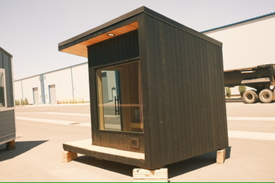 An archival photograph of a sauna on wood blocks outside the workshop