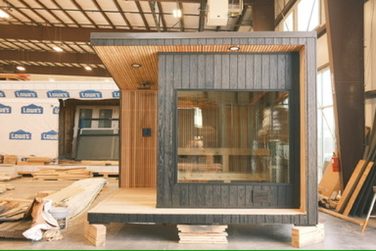 An archival photograph of a sauna supported on wood blocks inside the workshop