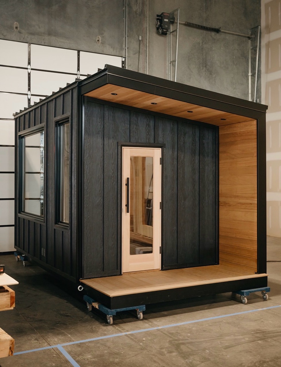 A dark-clad sauna on wheeled supports inside the factory