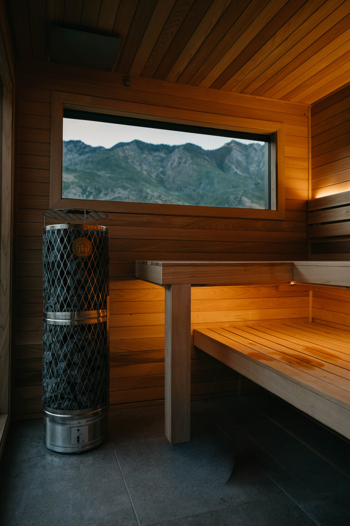 212 sauna interior, two-tier cedar bench beneath a mountain-view window