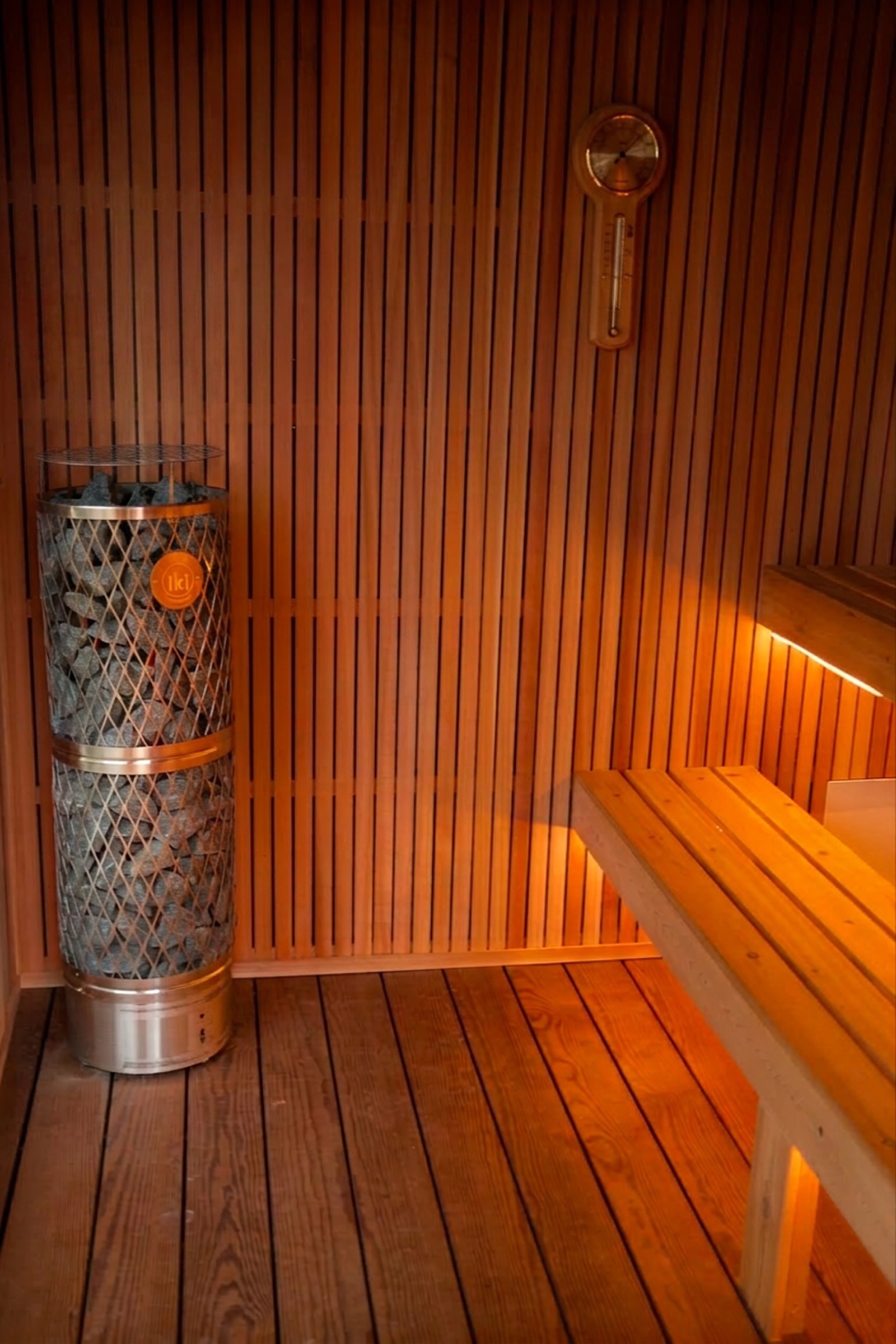 Inside the sauna room with cedar benches, backrest and stone-filled heater