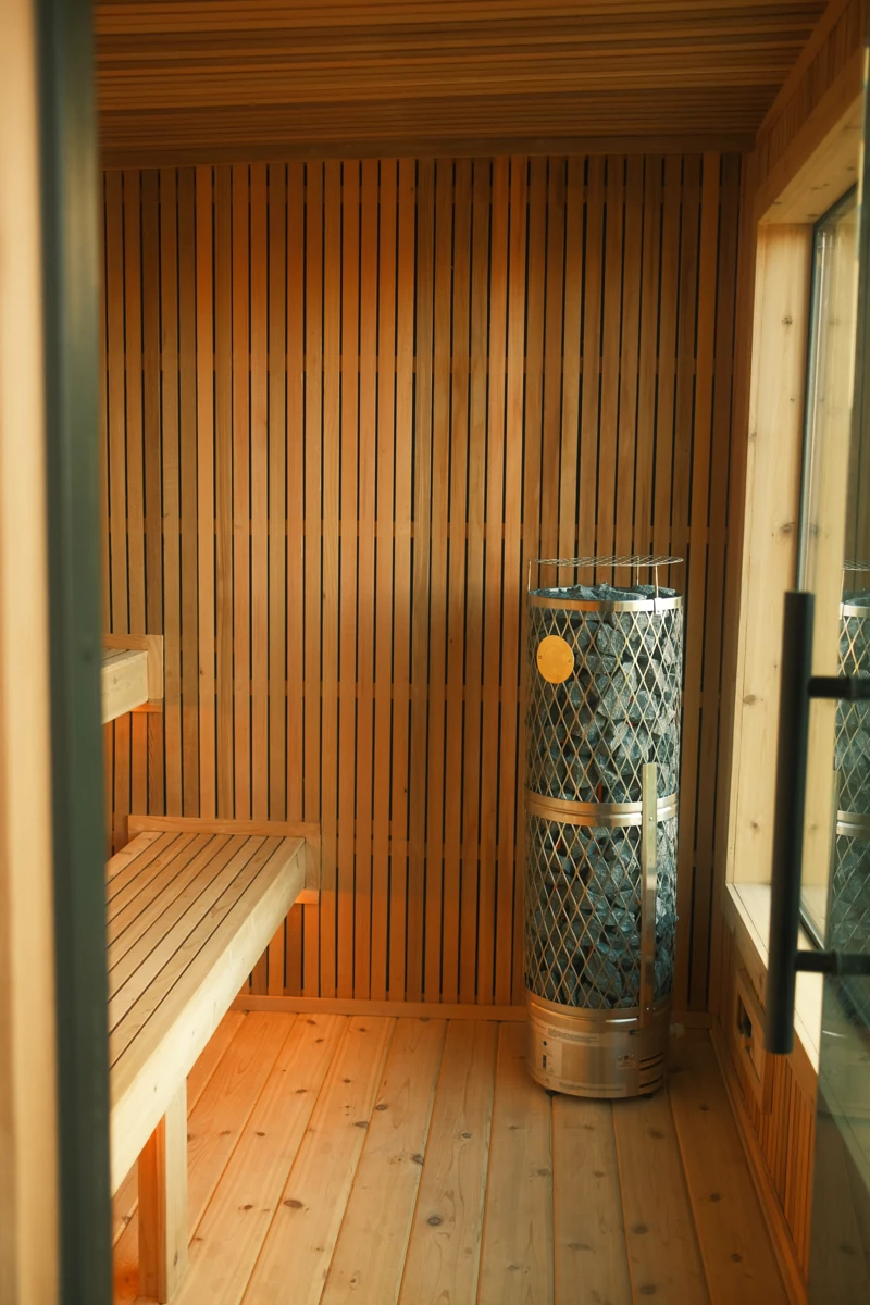 Full cedar sauna room with tiered benches, a large window and IKI heater