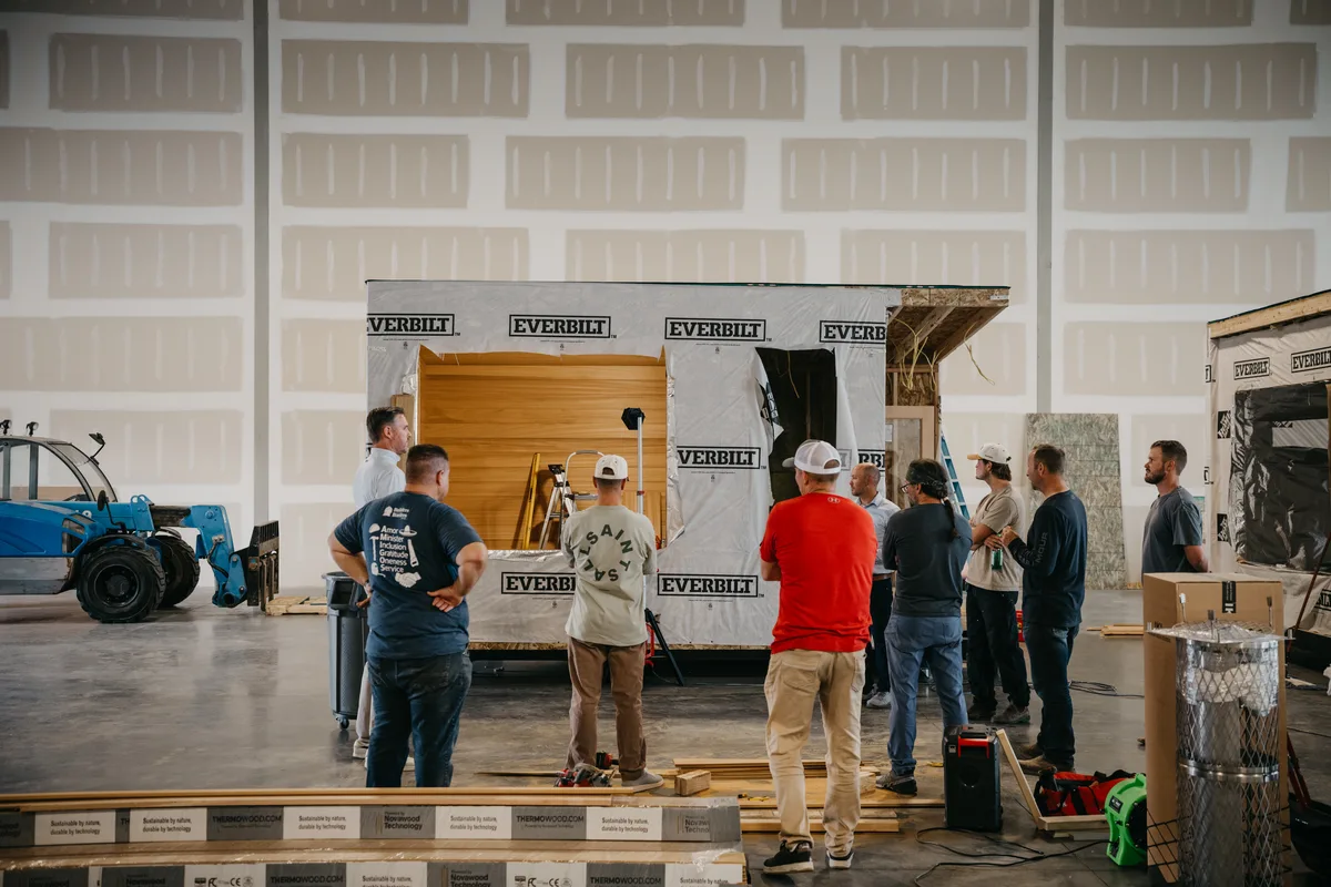 The New Primitive build team gathered around a wrapped sauna on the factory floor