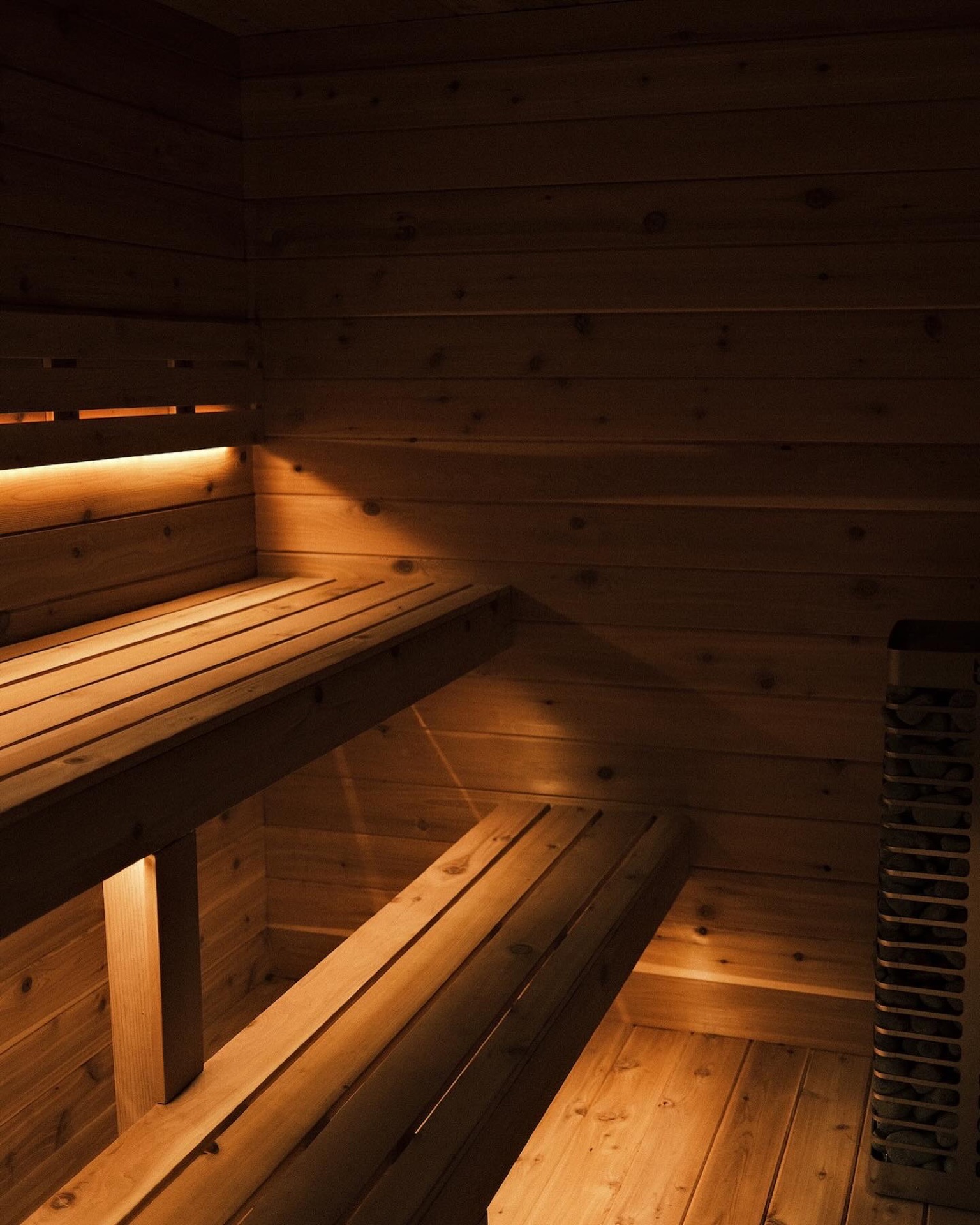A cedar sauna interior lit low and warm