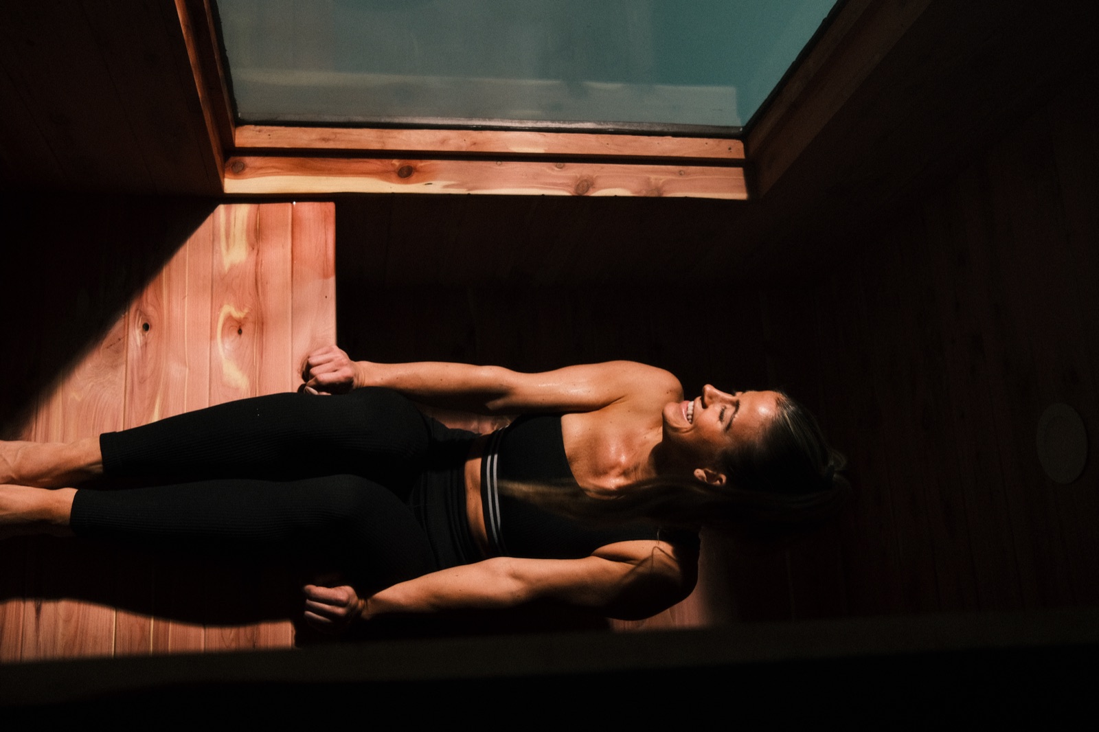 A sauna bench and floor washed in deep amber light